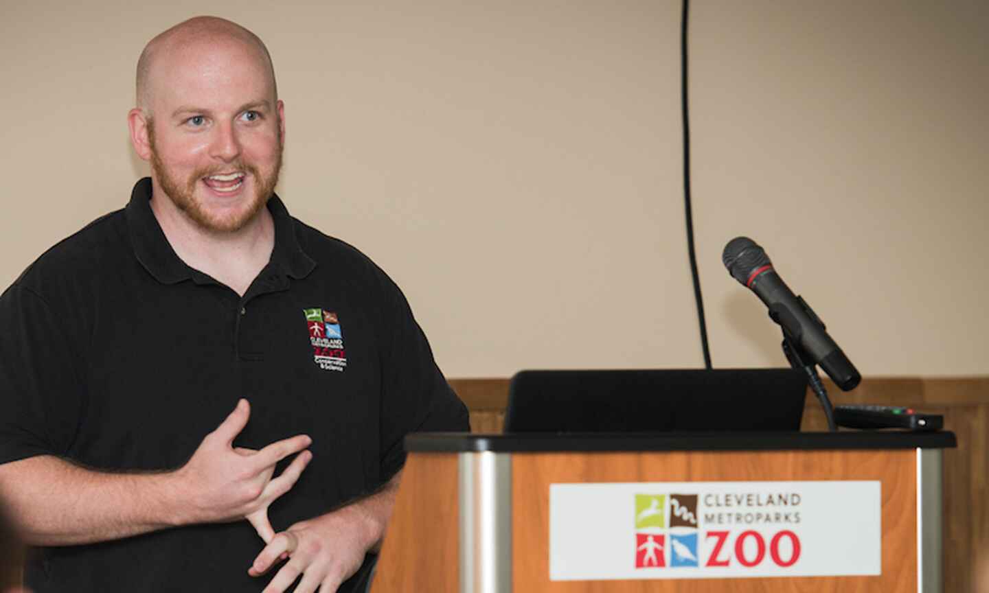 A zoo worker giving a speech behind a podium 