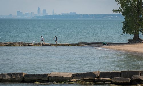 People walking on rock pier jutting out in Lake Erie