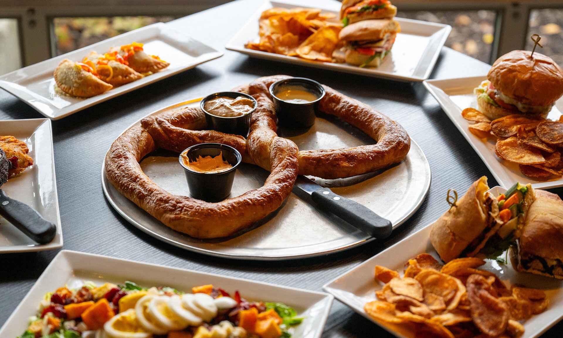 Pretzel with dips surrounded by other dishes