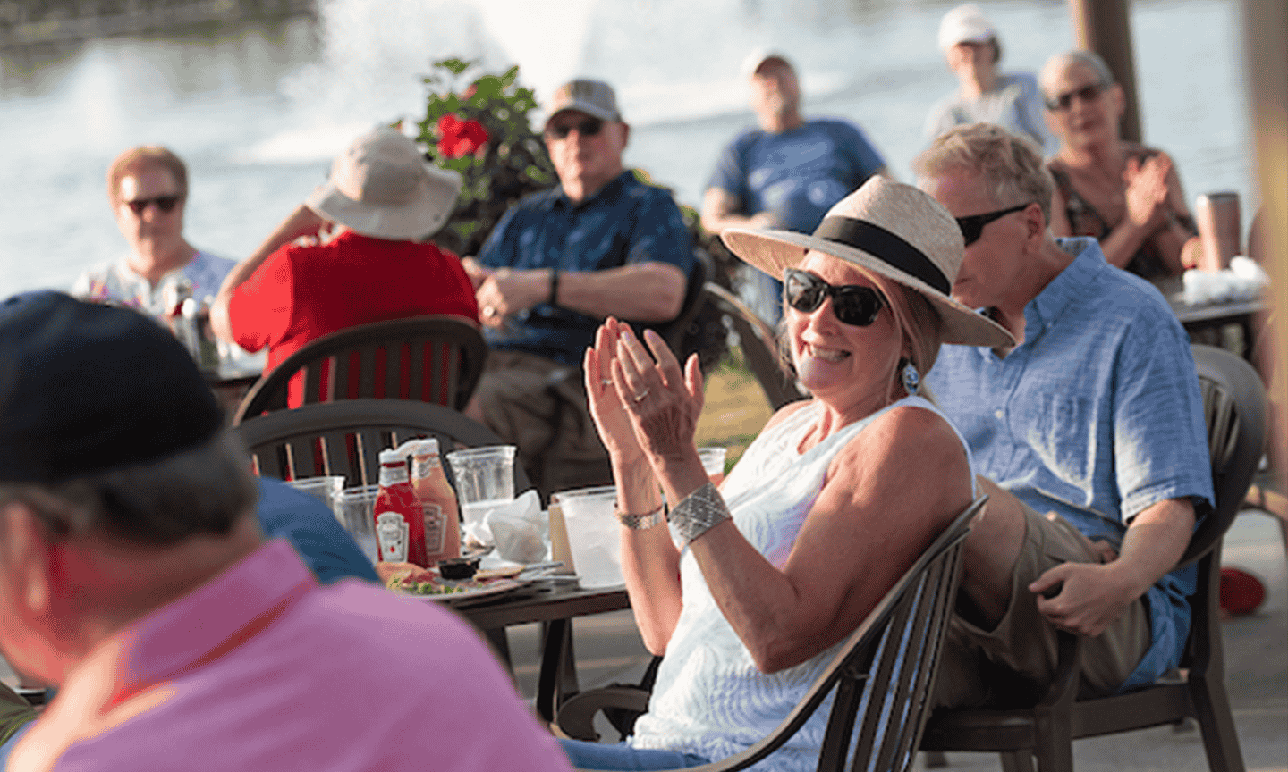 Woman clapping while sitting at on outdoor table at a restaurant 