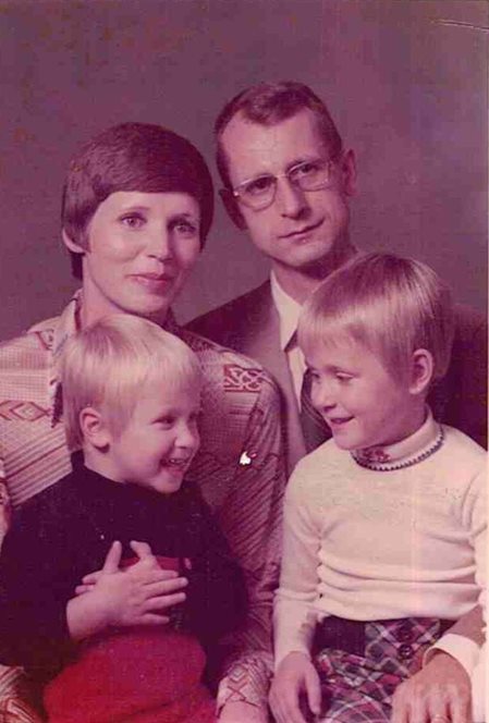 Vintage family portrait of the Bingel family, with two smiling children seated in front of their parents, who are looking at the camera.